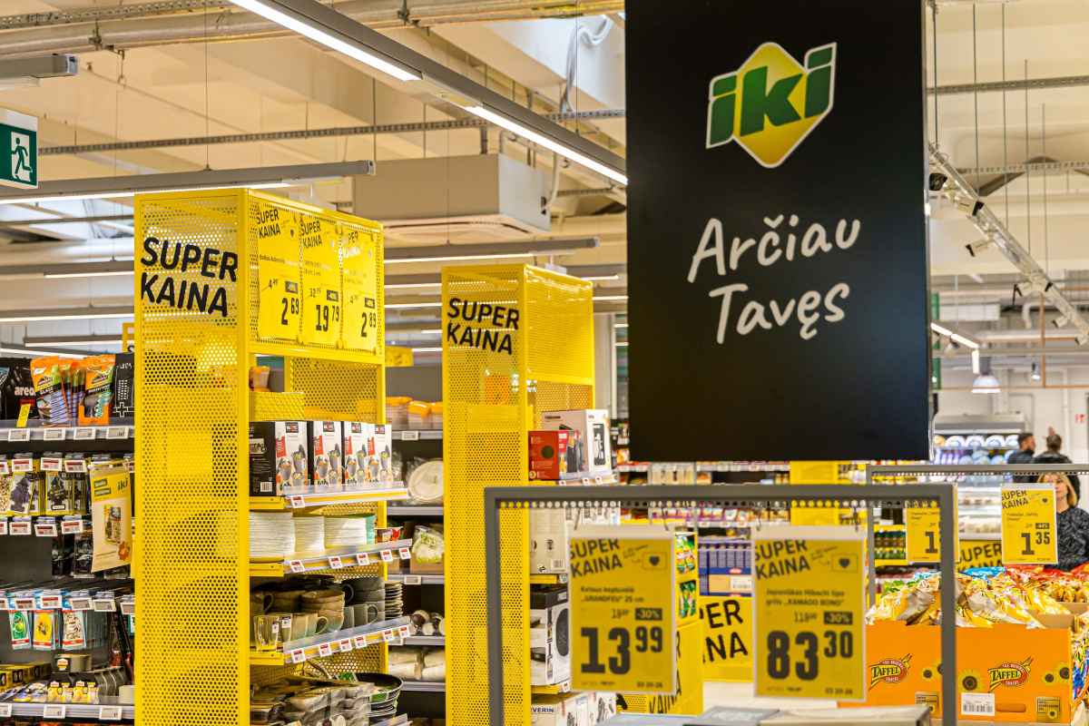 Prekybos centro lentynos su akcijų ženklais ir įvairiomis prekėmis.